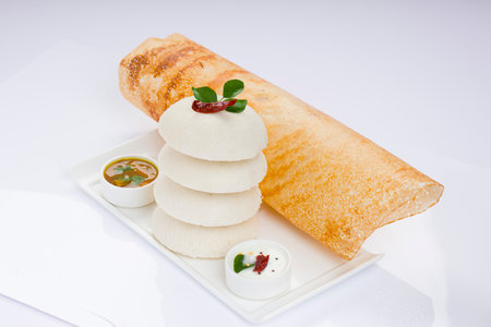 Ghee roast  Dosa and Idlii, south indian main breakfast item which is beautifully arranged in a white plate lined with banana leaf  and curry as sambar and chutney on white background.の写真素材