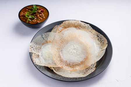 Appam or velliappam or kallappam  or paalappam, tasty delicious  breakfast item in south india and with a good combination of kadala curry or bengal gram curry ,placed on a white background.の写真素材