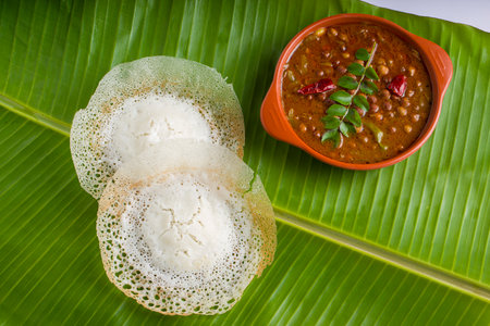 Appam or velliappam or kallappam  or paalappam, tasty delicious  breakfast item in south india and with a good combination of kadala curry or bengal gram curry ,placed on a banana leaf.の写真素材