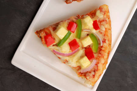 Pizza_Paneer Makhani , made using red and green bell pepper ,onion ,paneer and mozzarella cheese,thin pastry crust placed on white tableware with grey background,top view.の写真素材