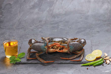 Live mud crab, arranged on a slate with and garnished with oil,lemon slices ,green chilli and fresh...