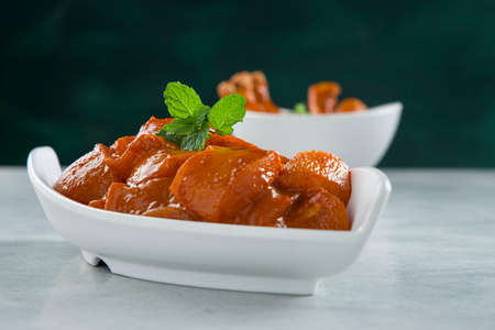 Raw marinated chicken cubes and legs or drum sticks arranged in a white ceramic tableware garnished with fresh coriander and mint leaf which is placed on grey white textured with dark green background,selective focus.の写真素材