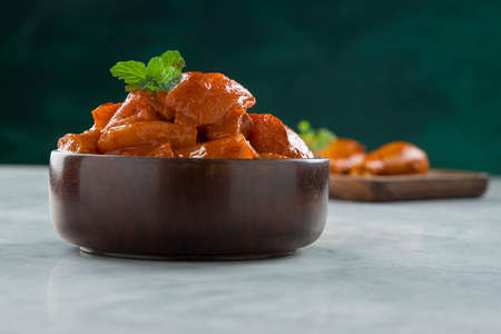 Raw marinated chicken cubes and drum sticks arranged in a wooden tableware garnished with fresh mint leaf which is placed on grey white texture and dark green background,selective focus.の写真素材