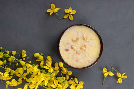 Vermecelli Payasam or Kheer ,South Indian main sweet dish made during special occassions using vermicelli ,milk,sugar and dry nuts  and beautifully arranged with golden shower flower in the grey background, selective focus.の写真素材