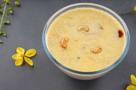 Vermecelli Payasam or Kheer ,South Indian main sweet dish made using vermicelli ,milk,sugar and dry nuts and arranged with golden shower flower in the grey background, selective focus.の写真素材