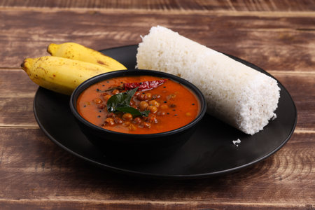 Puttu,Raw rice puttu,Arisi Maavu Puttu with chana or kadala curry, Bengal gram cuirry _breakfast items made using raw rice flour, an ideal combination arranged in a black plate with wooden backgroundの写真素材