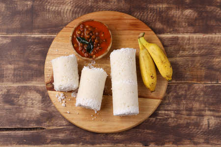 Puttu/Raw rice puttu/Arisi Maavu Puttu with chana curry/ kadala curry-Kerala special breakfast items made using raw rice flour, an ideal combination arranged in a wooden base with banana, on wooden background.の写真素材