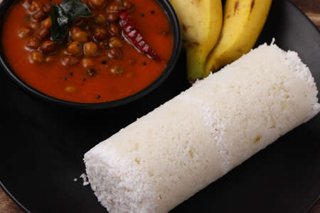 Puttu,Raw rice puttu,Arisi Maavu Puttu with chana or kadala curry, Bengal gram cuirry _breakfast items made using raw rice flour, an ideal combination arranged in a black plate with wooden backgroundの写真素材
