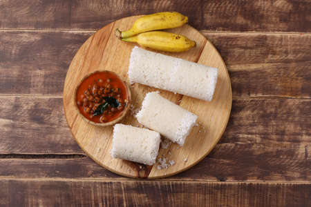Puttu/Raw rice puttu/Arisi Maavu Puttu with chana curry/ kadala curry-Kerala special breakfast items made using raw rice flour, an ideal combination arranged in a wooden base with banana, on wooden background.の写真素材
