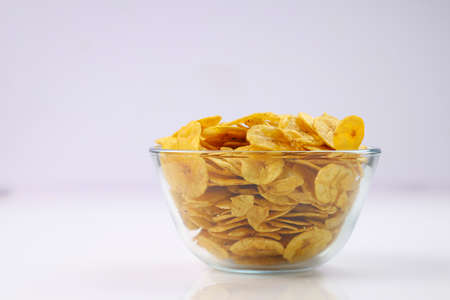 Dried banana chips or banana waffers,arranged beautifully in a glass bowl with white textured...