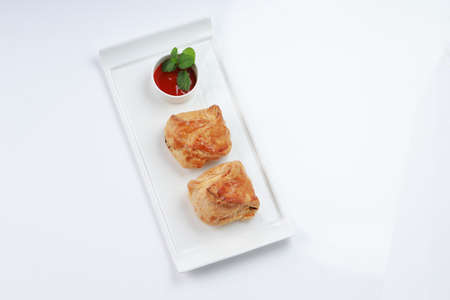 Egg Puff pastry filled with spicy and tasty egg masala and placed on a white tableware with tomato...