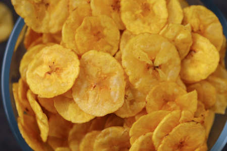 Dried banana chips or banana waffers,arranged beautifully in a glass bowl with grey  textured background, isolated.の写真素材