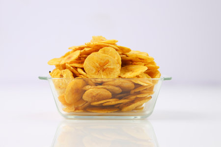 Dried banana chips or banana waffers,arranged beautifully in a glass bowl or tableware with white textured background, isolated.の写真素材