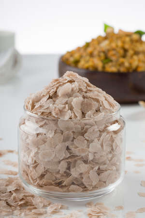 Raw poha or Aval placed with Aval upma or poha  upma or kanda poha upma,healthy indian breakfast item which is very tasty and easy to cook and it is arranged in a wooden bowl with white textured background.,selective focusの写真素材