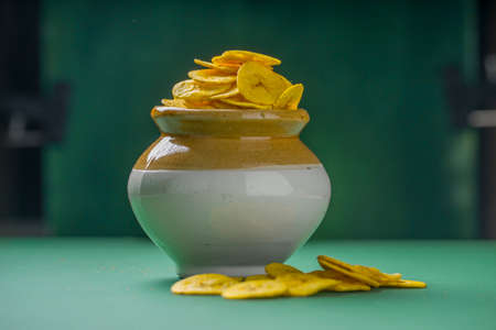 Dried banana chips or banana waffers,arranged beautifully in a clay and ceramic pot with  green  textured background.の写真素材