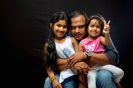 Potrait of an uncle with his two naughty niece, isolated on black background.の写真素材