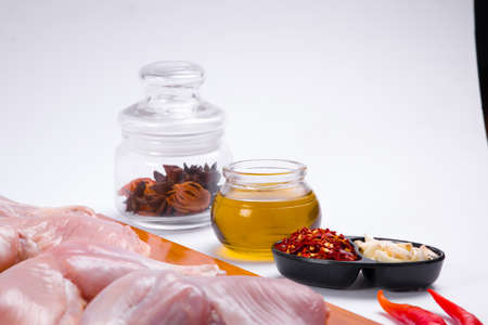 Raw whole chicken leg without skin arranged in wooden board and garnished with cooking ingrediants   on white textured  backgroundの写真素材