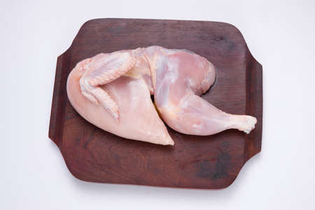 Raw half chicken without skin arranged on wooden board on white background