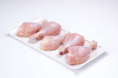 Raw chicken drum sticks arranged on white table ware  on white colour backgroundの写真素材