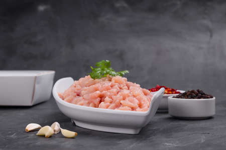 Raw chicken mince arranged in a white table ware and garnished with coriander leaf; chilly...
