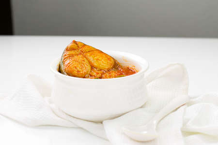 Seer Fish curry, traditional Indian fish curry ,kerala special ,arranged in a white bowl garnished...