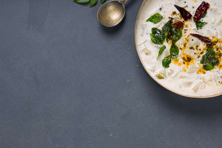 Pachadi or Raitha_south Indian side dish made using ash guard, curd and coconut placed in a brass...