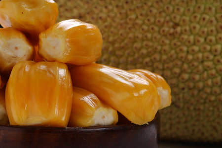 Ripe Jackfruit arranged beautifully in a wooden bowl  with white textured background.
