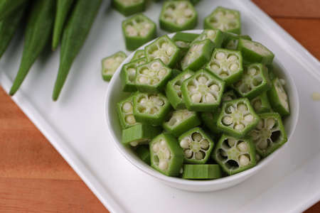Okra or Lady's finger or Bhindi fresh green vegetable arranged  on a white tableware with a  bowl...