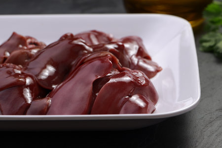 Raw chicken liver arranged beautifully in a white ceramic plate placed on a grey textured  background,closeupの写真素材