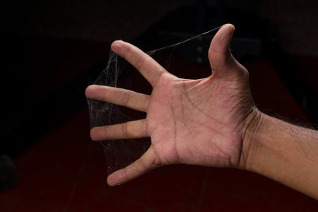 A man fingers covered with spider web on black backgroundの写真素材