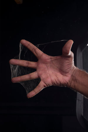 A man fingers covered with spider web on black backgroundの写真素材