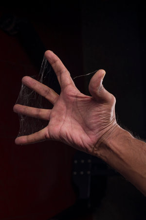 A man fingers covered with spider web on black backgroundの写真素材