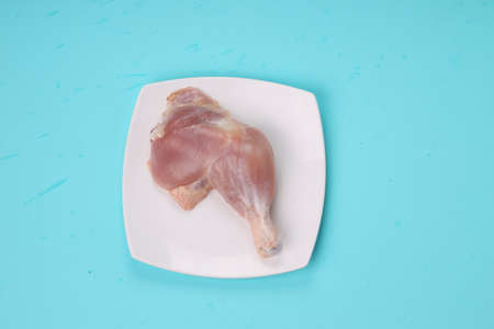 Raw whole chicken leg without skin arranged  in a square shape white tableware with ice blue solid colour background.の写真素材