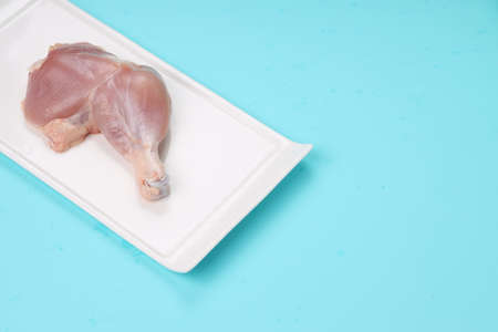 Raw whole chicken leg without skin arranged rectangle shape flat tableware with ice blue solid colour backgroundの写真素材