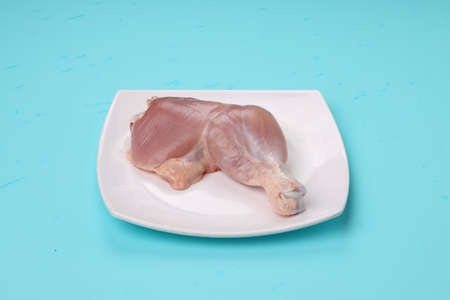 Raw whole chicken leg without skin arranged  in a square shape white tableware with ice blue solid...