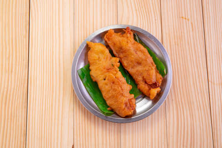 Banana fritters or banana fry or Pazham pori,Indian fried snack,isolated on steel plate lined with...