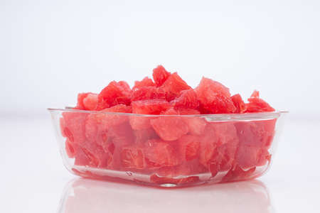 Watermelon Slices,cutpiece  of watermelon arranged in a transparent square glass bowl  with white rustic  background, isolated.の写真素材