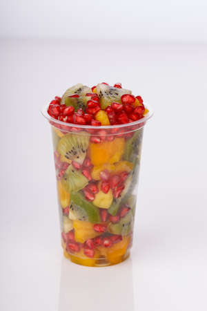 Mixed cut fruits arranged in a transparent glass with white background, isolated.の写真素材