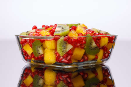 Mixed cut fruits arranged in a transparent glass bowl  with black background, isolated.