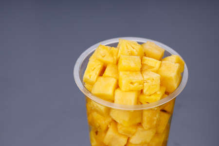 Pineapple cubes arranged in transparent glass with black backgroundの写真素材