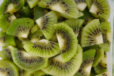 Kiwi fruit slices or cut piece arranged in a glass square container with white color background.の写真素材