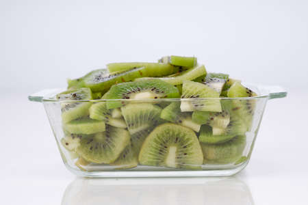 Kiwi fruit slices or cut piece arranged in a glass square container with white color background.の写真素材