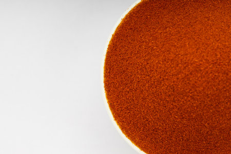 Red chilly powder ,Indian spice;arranged in a white bowl  with white texture or background