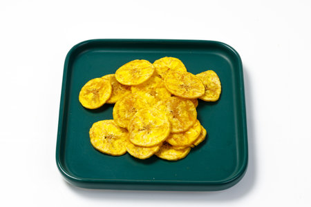 Kerala chips or Banana chips, cult snack item of Kerala, arranged in a green ceramic square shaped plate ,Isolated image with white backgroundの写真素材