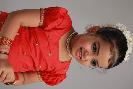 A cute small girl child wearing  Kerala dress-golden colour long skirt and red blouse with golden...
