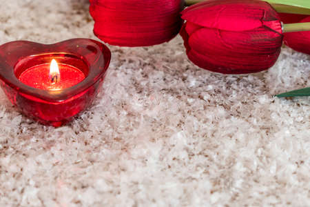 Tulip flower and heart shaped candle on an snow like background. Valentine Day Concept.の写真素材