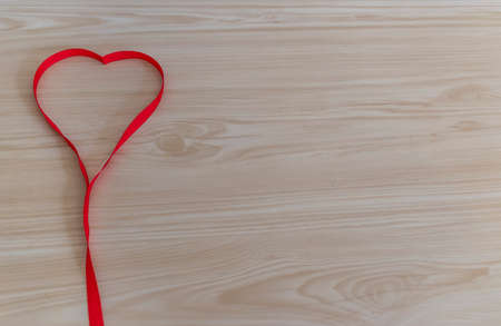 Red ribbon heart on wooden background, Valentine Day Concept.