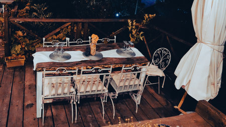 Elegant table set for dinner on the terrace garden, placemat on the table, wine glasses, dried...