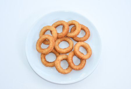 fried onion rings on white plate isolated on white background, top view
