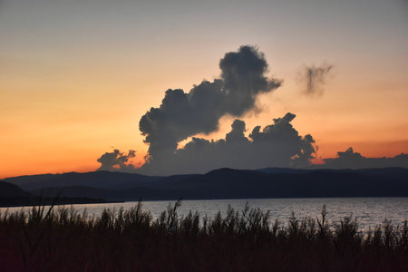 Sunset on the lake in the tropics with a large cloud in the skyの写真素材